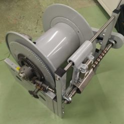 En Slangvinda modell För 50m Ø2" slang- Motordriven 24VDC rulle står på ett bord i ett rum.